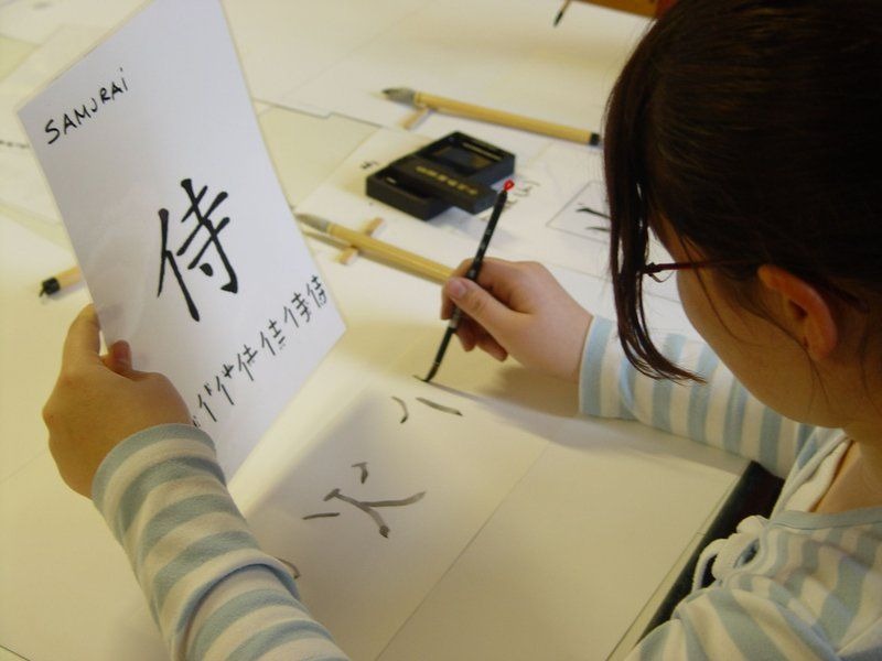Jugendliche übt Kalligraphie mit Pinsel und schreibt japanische Schriftzeichen