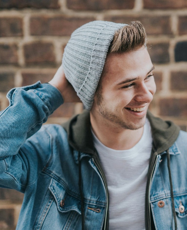 Lachender junger Mann mit Mütze